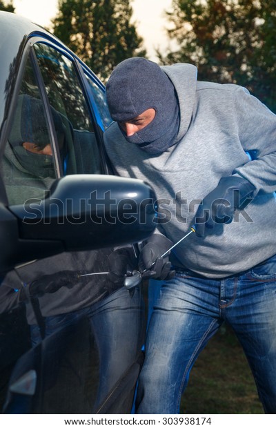 Car thief\
stealing a car. Breaking the\
lock.