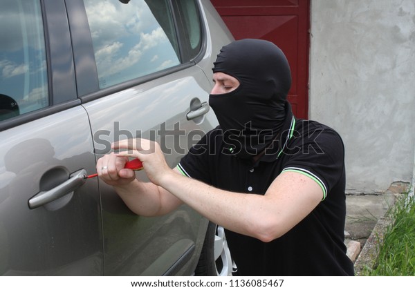 Car\
thief trying to break into a car with a\
screwdriver.