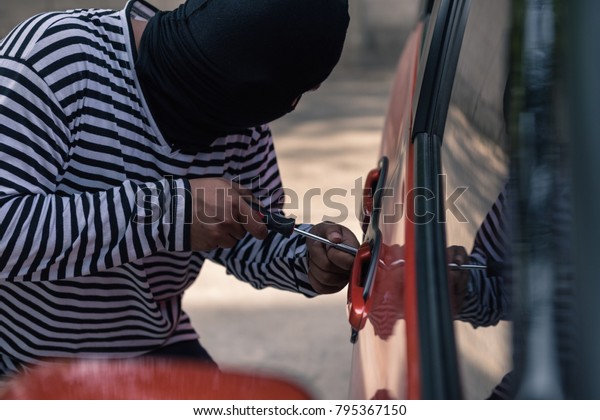 Car thief\
trying to unlock a car by\
screwdriver.