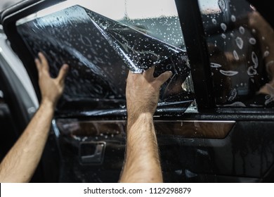 Car tinting - Worker applying tinting foil on car window. 