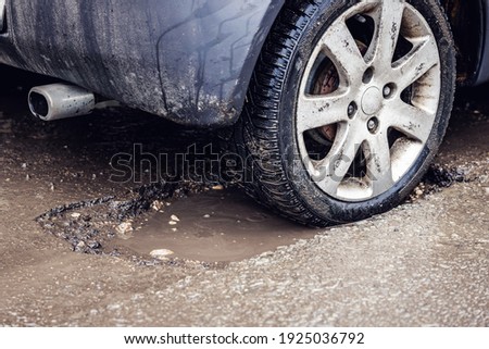 car tire in big pothole on the road