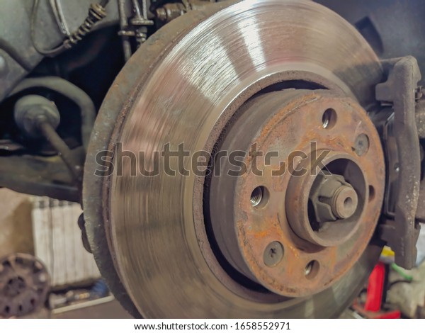 Car tire disk with the rubber tire missing in a\
mechanics professional workshop for tire changing when seasons are\
changing for safe driving