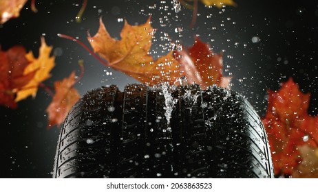 Car Tire With Falling Autumn Leaves And Splashing Water, Macro Photo, Weather Concept. Studio Photo, Free Space For Text.