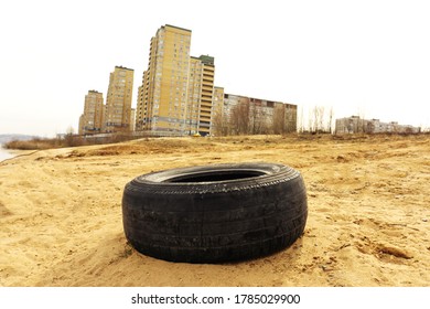 The Car Tire Lies Against The Backdrop Of City Houses. Environmental Pollution By Law And Order Violators