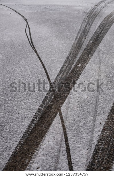 Car tire marks in light snow on asphalt\
together with bike tire mark. Winter\
scene