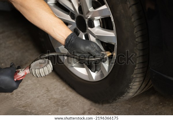 Car tire pressure check using air pressure\
guage. Mechanic inflating a car tire. Gas pumping of a car wheel.\
Car tire inflation.