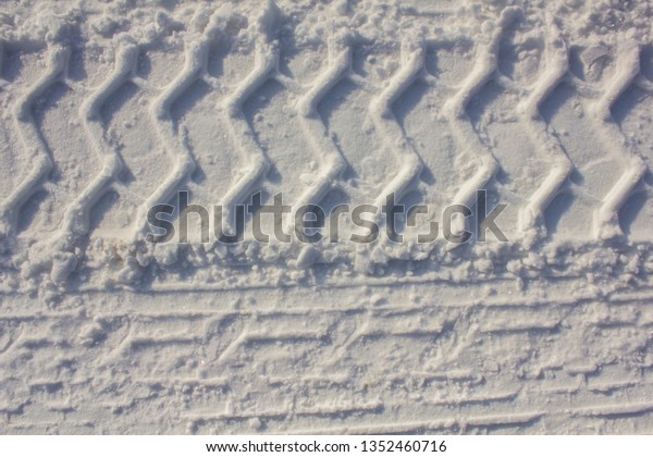 car tire prints on white snow close-up. rough\
surface texture
