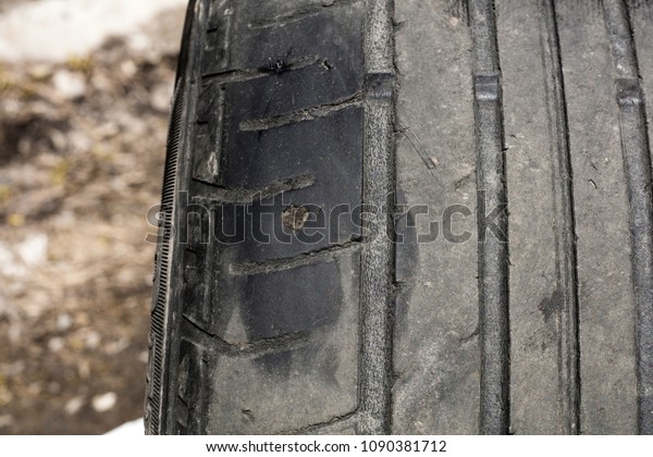 Car tire repair. A puncture of an old car tire with\
a small tread depth