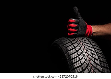 Car tire service and hands of mechanic holding new tyre on black background with copy space for text - Powered by Shutterstock