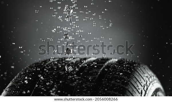 Car tire with\
splashing water in detail, macro photo, weather concept. Studio\
photo, Free space for text.