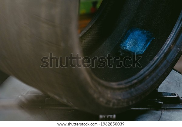 A car tire in\
a workshop with its rim\
removed
