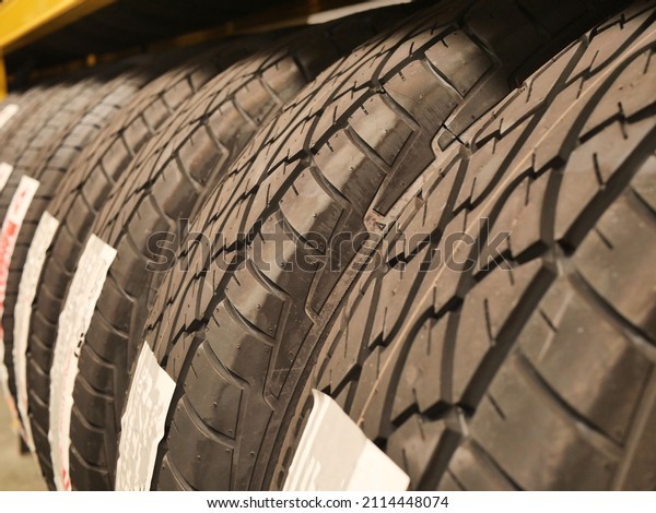 Car tires\
background in a row.  Car tires at warehouse in tire store . Car\
tires on rack in auto store,\
closeup