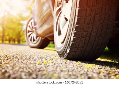 Car tires closeup on asphalt road on summer day at park