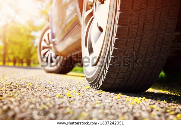 Car\
tires closeup on asphalt road on summer day at\
park