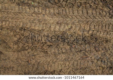Car tires imprints in muddy ground. Vehicle tire rut in forest footpath. 
Automobile tyre ectype in field mould. Motor car rubber engram in the soil. Squeeze of car rubber tire in the forest ground