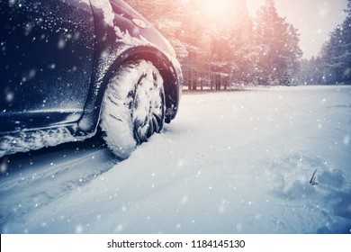 Car tires on winter road covered with snow. Vehicle on snowy way in the morning at snowfall