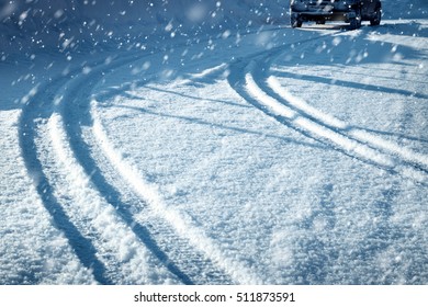 Car tires on winter road covered with snow. Vehicle on snowy alley in the morning at snowfall