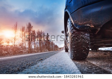 Car tires on winter road covered with snow. Vehicle on snowy way in the morning