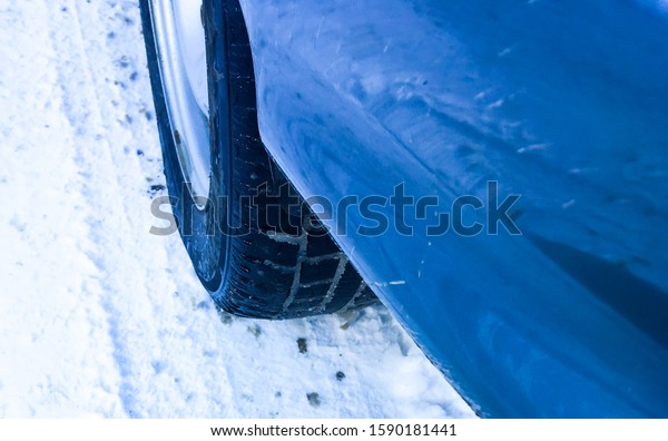 Car tires on a winter road covered\
in snow. Car on a snowy path in the morning with\
snowfall