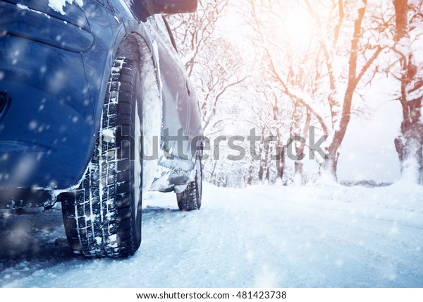 Car tires on winter road covered\
with snow. Vehicle on snowy alley in the morning at\
snowfall