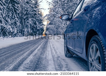 Car tires on a winter snow - covered forest road . Winter landscape with a blue car in the forest.