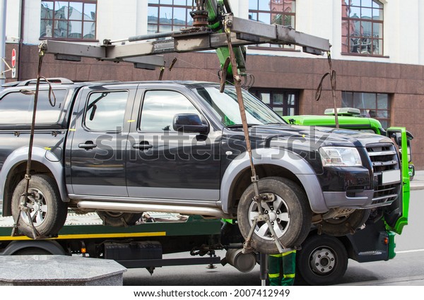 Car tow truck lifted car for loading. Parking\
violation in city