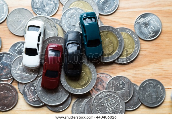 Car toy on coins and wood background. used for\
background or material \
design.
