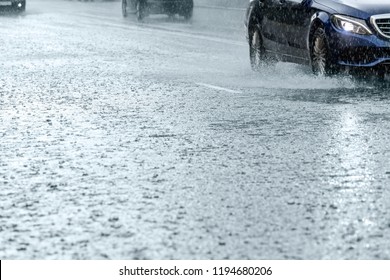 Car Traffic Driving On Flooded City Road During Rain. Water Splashing From Car Wheels