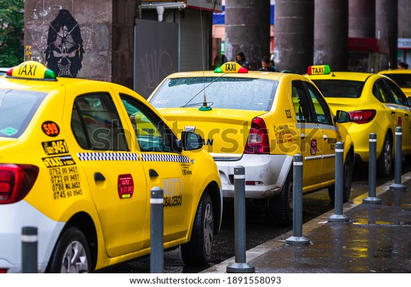 Car in traffic, modern city taxi service. Taxi cars\
parked at the taxi station in the capital city of Bucharest,\
Romania, 2020