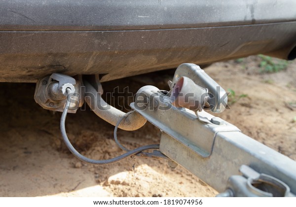 Car\
trailer coupling with trailer lock handle and electrical socket\
close up rear view, safety driving with a\
trailer