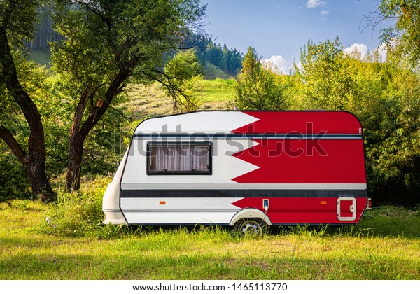 A car trailer, a motor home, painted in the national\
flag of Bahrain stands parked in a mountainous. The concept of road\
transport, trade, export and import between countries. Travel by\
car