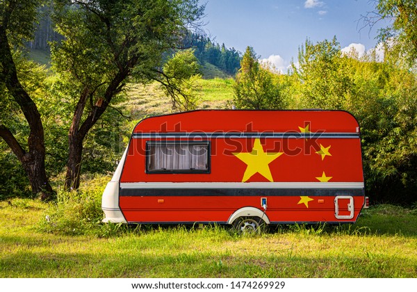 A car trailer, a motor home, painted in the national\
flag of  China\
 stands parked in a mountainous. The concept of\
road transport, trade, export and import between countries. Travel\
by car