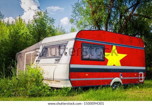 A car\
trailer, a motor home, painted in the national flag of  Vietnam\
stands parked in a mountainous. The concept of road transport,\
trade, export and import between\
countries.