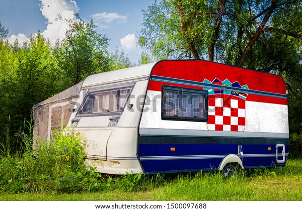 A car\
trailer, a motor home, painted in the national flag of  Croatia\
stands parked in a mountainous. The concept of road transport,\
trade, export and import between\
countries.