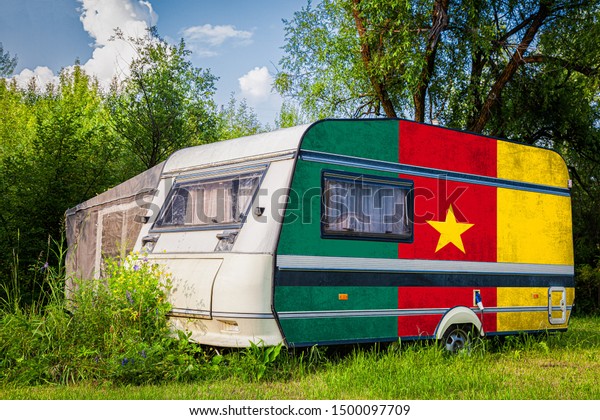 A\
car trailer, a motor home, painted in the national flag of \
Cameroon stands parked in a mountainous. The concept of road\
transport, trade, export and import between\
countries.