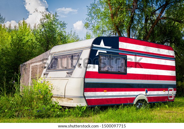 A car\
trailer, a motor home, painted in the national flag of  Liberia\
stands parked in a mountainous. The concept of road transport,\
trade, export and import between\
countries.