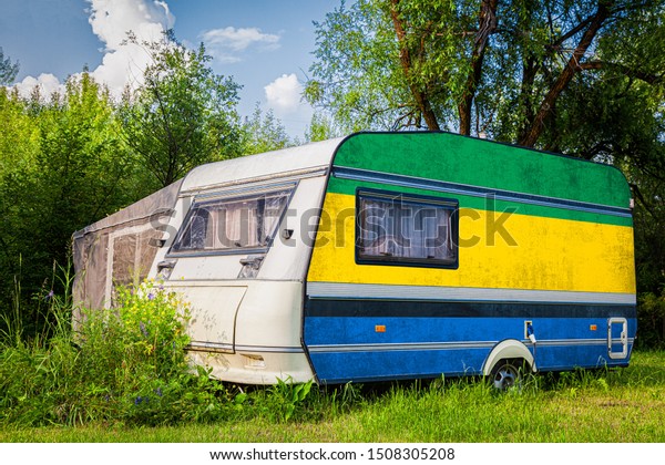 A car\
trailer, a motor home, painted in the national flag of  Gabon\
stands parked in a mountainous. The concept of road transport,\
trade, export and import between\
countries.