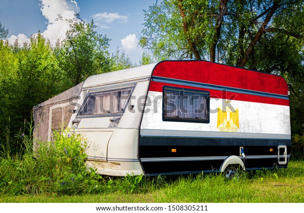 A car\
trailer, a motor home, painted in the national flag of  Egypt\
stands parked in a mountainous. The concept of road transport,\
trade, export and import between\
countries.