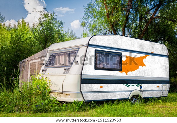 A car\
trailer, a motor home, painted in the national flag of  Cyprus\
stands parked in a mountainous. The concept of road transport,\
trade, export and import between\
countries.