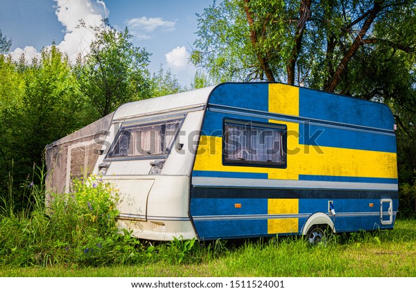 A car\
trailer, a motor home, painted in the national flag of  Sweden\
stands parked in a mountainous. The concept of road transport,\
trade, export and import between\
countries.