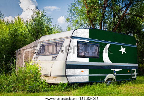 A\
car trailer, a motor home, painted in the national flag of \
Pakistan stands parked in a mountainous. The concept of road\
transport, trade, export and import between\
countries.