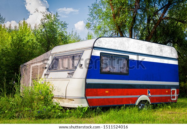 A car\
trailer, a motor home, painted in the national flag of  Russia\
stands parked in a mountainous. The concept of road transport,\
trade, export and import between\
countries.