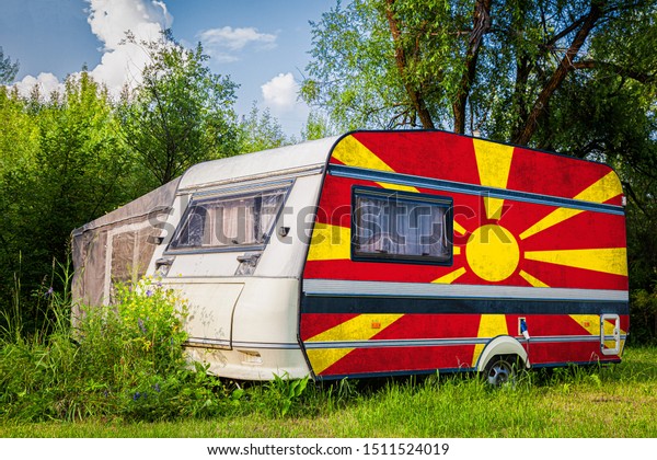 A\
car trailer, a motor home, painted in the national flag of\
Macedonia stands parked in a mountainous. The concept of road\
transport, trade, export and import between\
countries.