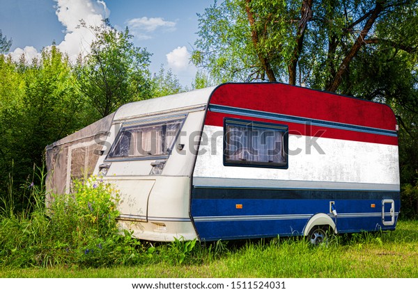 A
car trailer, a motor home, painted in the national flag of 
Netherlands stands parked in a mountainous. The concept of road
transport, trade, export and import between
countries.