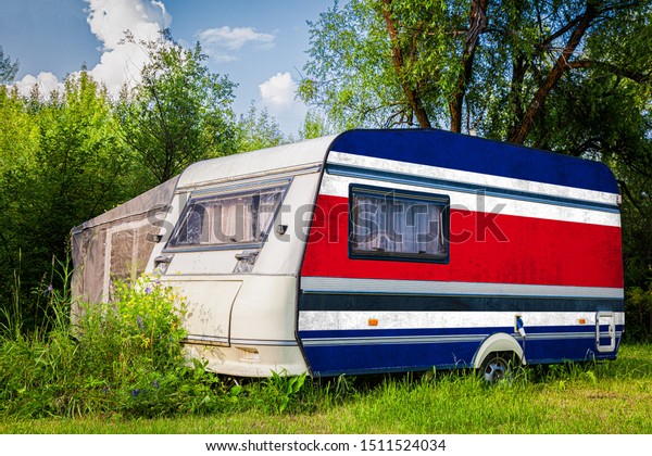 A car\
trailer, a motor home, painted in the national flag of  Costa Rica\
stands parked in a mountainous. The concept of road transport,\
trade, export and import between\
countries.