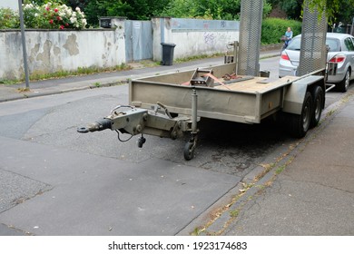 a car trailer is parked in front of a small car on the side of the road