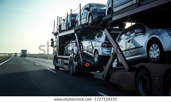 Car transporter trailer loaded with many cars on\
a highway, motion blur\
effect.