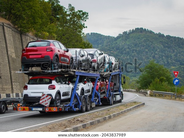 Car transporter transports new cars to the\
showroom. Cars arranged on two levels. Cars of different colors.No\
logo or brand.