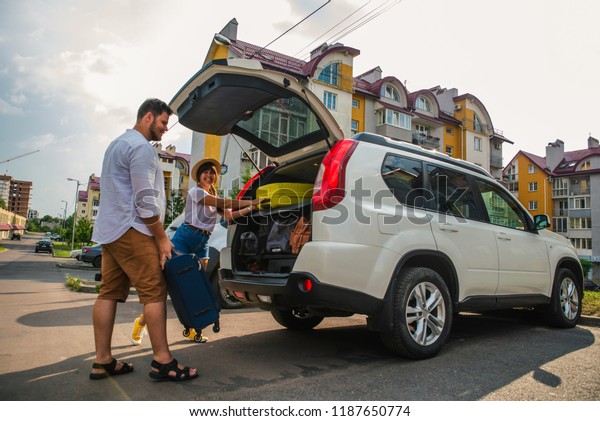 car travel concept. opened trunk with\
luggage inside woman with man near it. road\
trip