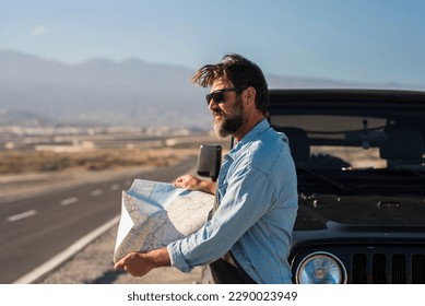 Car travel tourism concept, One tourist outside the vehicle with paper guide map find roads to arrive at destination. Adventure vacation explorer lifestyle people. Black off road. Straight long road - Powered by Shutterstock